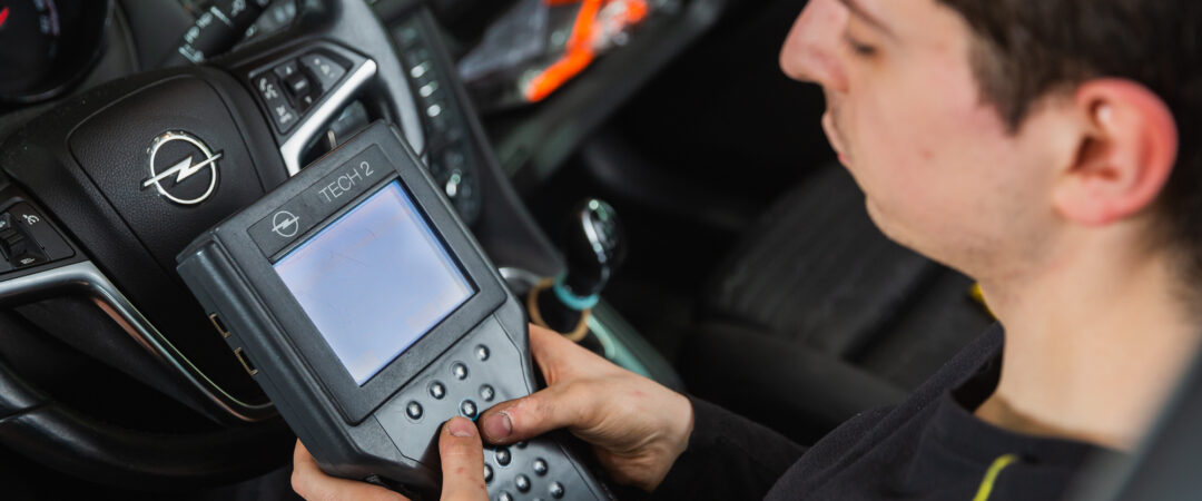 Mechaniker nutzt ein OBD-Diagnosegerät im Innenraum eines Opel-Fahrzeugs zur Fahrzeuganalyse.