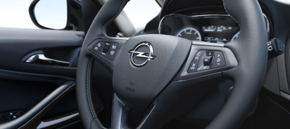 Nahaufnahme eines Opel-Lenkrads mit Multifunktionstasten im modernen Fahrzeuginnenraum.